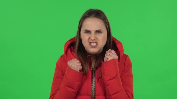 Porträt eines hübschen Mädchens in einer roten Daunenjacke, das genervt gestikuliert und in Stress Irritationen und Wut ausdrückt. Green Screen — Stockvideo