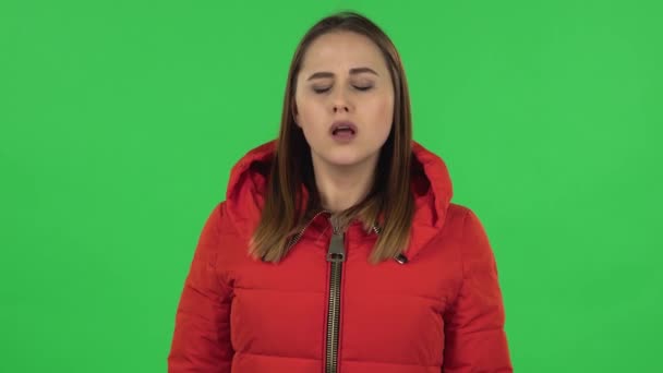 Retrato de una chica encantadora en una chaqueta roja molesta y encogiéndose de hombros. Pantalla verde — Vídeos de Stock