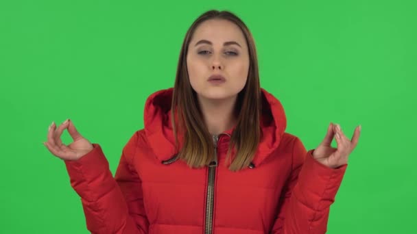 Porträt der schönen Mädchen in einer roten Daunenjacke entspannt, meditiert im Studio. Green Screen — Stockvideo