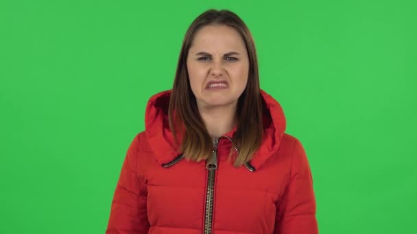 Retrato de chica encantadora en una chaqueta roja abajo está mostrando disgusto por el mal olor o el gusto. Pantalla verde — Vídeo de stock