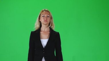Blonde girl in a black jacket going and looking straight into the camera against a green screen. Slow motion