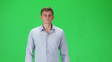 Young man in a gray shirt going and looking forward against a green background. Slow motion.