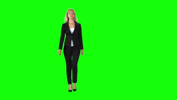 Blonde girl in a black suit, white blouse and high-heeled shoes going against a green screen. — Stockvideo