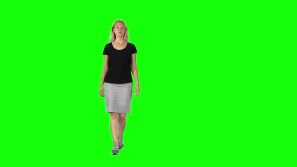 Блондинка в черной футболке, серая юбка и кроссовки идут против зеленого экрана . — стоковое видео