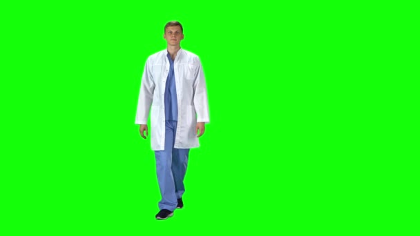 Medical man in white coat going and looking forward against a green background. — Wideo stockowe