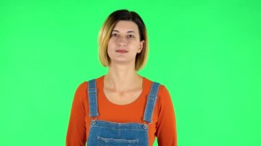 Kadın ayakta duruyor, gülümseyerek yayılıyor ve kameraya bakıyor. Yeşil Ekran