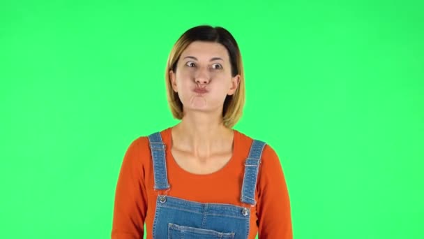 Trendy girl poses for camera makes funny faces. Green screen — Stockvideo