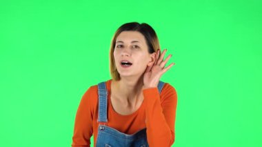 Woman holding hand near ear trying to listen to interesting news expressing communication concept. Green screen