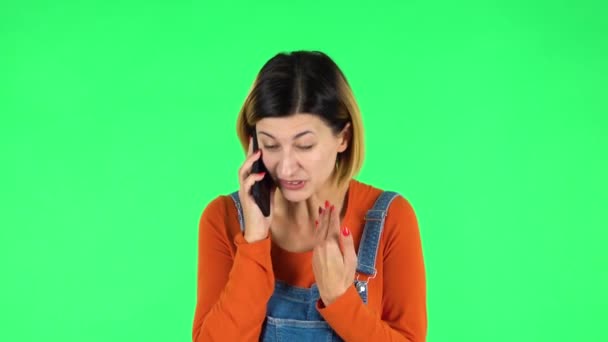 Het meisje spreekt boos aan de telefoon, bewijst iets. Groen scherm — Stockvideo