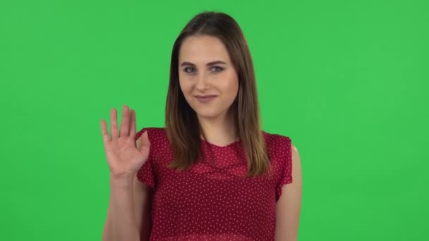 Portrait of tender girl in red dress is waving hand and showing gesture come here, flirting. Green screen — Stockvideo