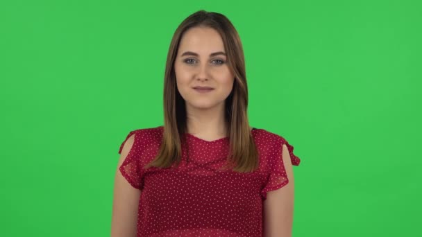 Portrét něžné dívky v červených šatech se usmívá a ukazuje srdce s prsty pak fouká polibek. Zelená obrazovka — Stock video