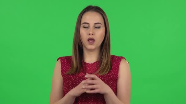 Portrait of tender girl in red dress is clapping her hands indifferent. Green screen — ストック動画