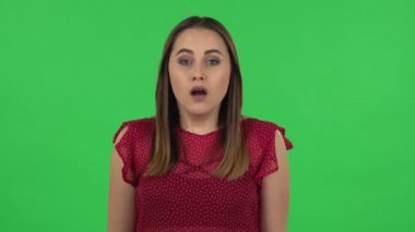Portrait of tender girl in red dress is looking at camera with anticipation, then very upset. Green screen