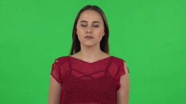 Portrait of tender girl carefully examines something then fearfully covers her face with her hand. Green screen