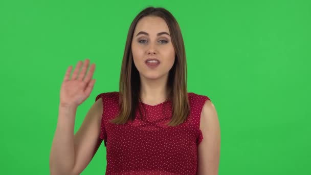 Portrait of tender girl in red dress is waving hand and showing gesture come here. Green screen — 图库视频影像