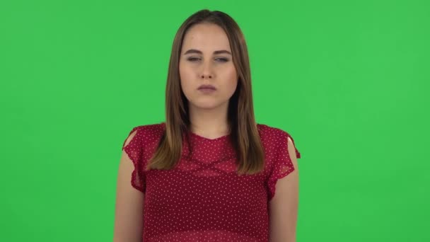 Portrait of tender girl in red dress is thinking about something, and then an idea coming to her. Green screen — ストック動画