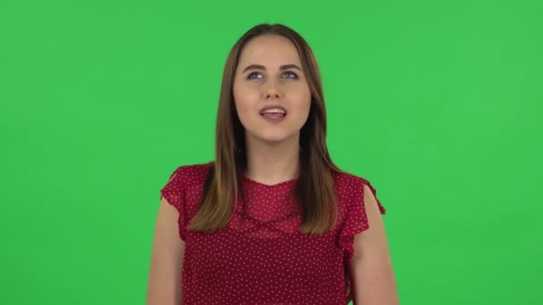 Portrait of tender girl in red dress is daydreaming and smiling looking up. Green screen — Stockvideo