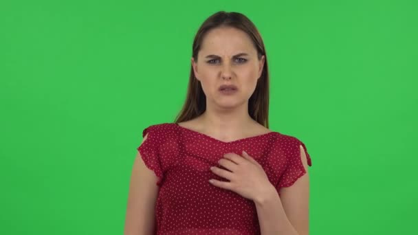 Portrait of tender girl in red dress is showing disgust for bad smell or taste. Green screen — ストック動画