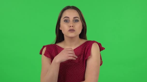 Portrait de fille tendre en robe rouge écoute attentivement et hochant la tête pointant du doigt le spectateur. Écran vert — Video