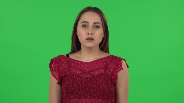 Портрет нежной девушки в красном платье расстроен и вздыхает. Зеленый экран — стоковое видео