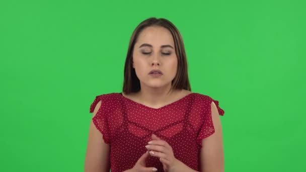Portrait of tender girl in red dress is listening to information, shocked and very upset. Green screen — Αρχείο Βίντεο