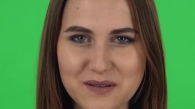 Woman looking straight, smiling and raises an eyebrow flirting. Close up. Green screen