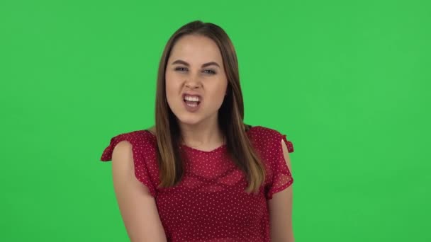 Portrait of tender girl in red dress is threatening with a fist. Green screen — Stockvideo