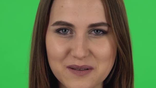 Woman looking straight, smiling and raises an eyebrow flirting. Close up. Green screen — Stock video