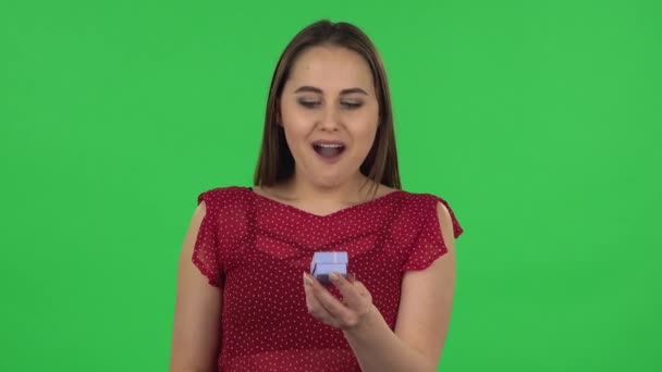 Portrait of tender girl is opening a small box with a surprise and is very rejoicing, saying yes. Green screen — Stock videók