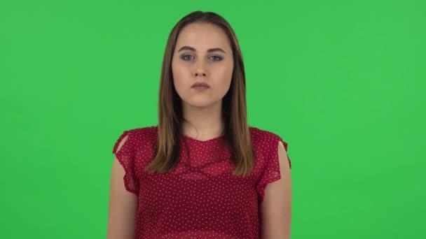 Portrait of tender girl in red dress is looking at the camera with excitement, then celebrating her victory. Greenscreen — Stock Video