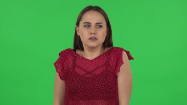 Portrait of tender girl in red dress girl froze and trying to keep warm. Green screen