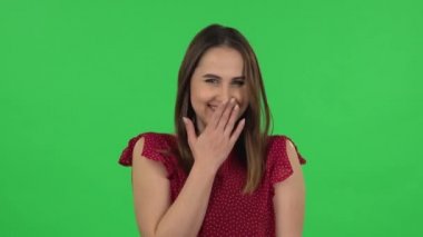 Portrait of tender girl in red dress is pointing herself, say who me no thanks i do not need and laughing. Green screen