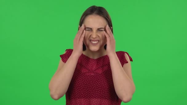 Portré érzékeny lány piros ruhában szenved fejfájás fáradtság. Zöld képernyő — Stock videók