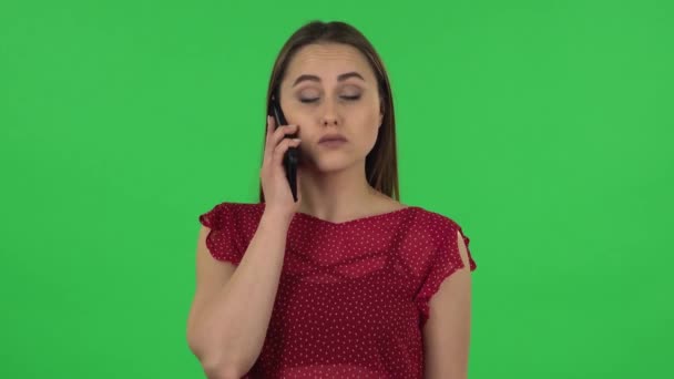 Portrait of tender girl in red dress is talking for mobile. Green screen — Wideo stockowe