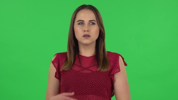 Portrait of tender girl in red dress is focused thinking about something, no idea. Green screen — ストック動画