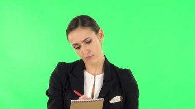 Kız ayağa kalkar ve düşünür, sonra da öfkeyle deftere kalemle yazar. Yeşil Ekran