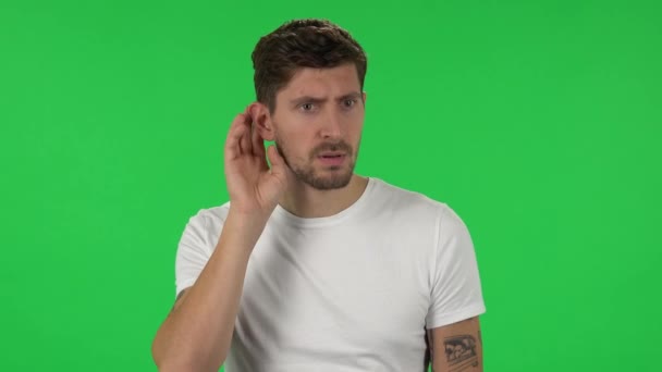 Portrét sebevědomého chlapa se drží za ruku u ucha a snaží se poslouchat zajímavé zprávy vyjadřující koncept komunikace. Zelená obrazovka — Stock video
