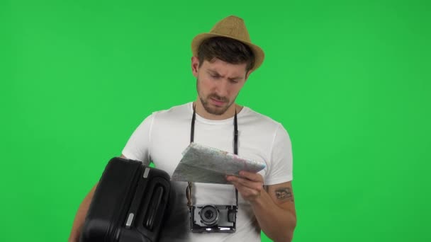 Портрет туриста с чемоданом и ретро камерой тщательно изучает карту, затем смотрит в камеру с разочарованием . — стоковое видео