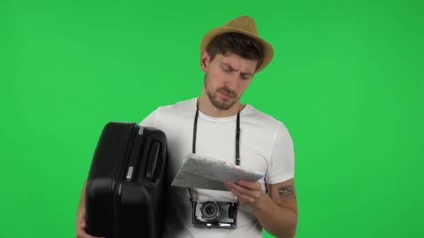 Portrait de touriste avec valise examine attentivement la carte, puis en regardant la caméra avec expression faciale choquée. Écran vert — Video