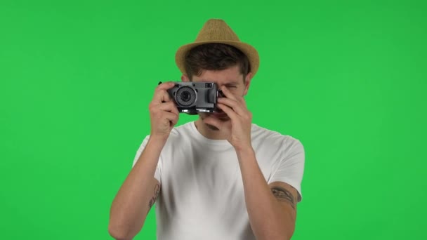 Портрет туриста в шляпе на отдыхе фотографирует на ретро-камеру. Зеленый экран — стоковое видео
