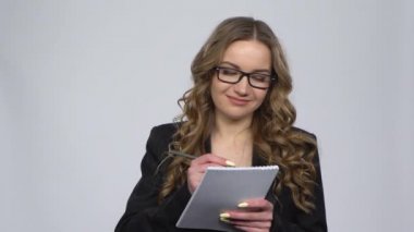 Kadın deftere şemalar çizer sonra da hayal kırıklığı yaratacak şekilde gri arkaplanda omuz silker.