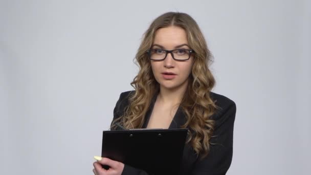 Žena kancelářský pracovník držící schránku se rozhlédne a dělá si poznámky přes šedé pozadí — Stock video
