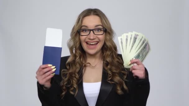 Chica está sosteniendo pasaporte, billete de avión y dinero muy regocijo y disfrutando en fondo gris — Vídeos de Stock