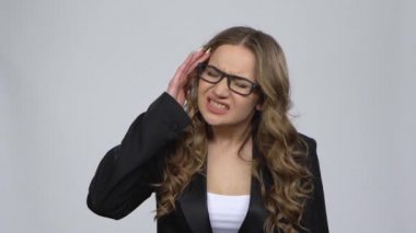 İş kadını, gri arka planda yorgunluktan baş ağrısı çekiyor.