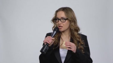 Çekici kız mikrofona şarkı söylüyor ve gri arka planda müziğin ritmine geçiyor.