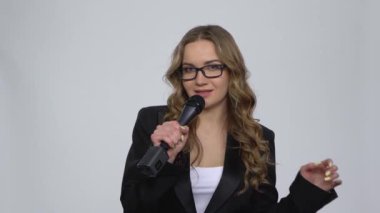 Çekici kız mikrofona şarkı söylüyor ve gri arka planda müziğin ritmine geçiyor.