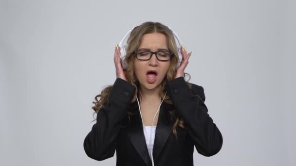 Woman dancing enjoy music in big white earphones on gray background at studio — Stock Video