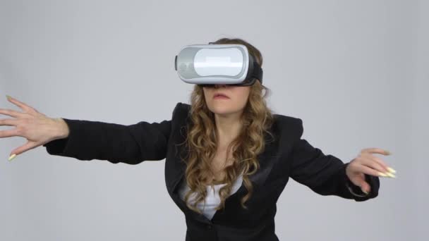 Jonge vrouw met virtual reality bril op haar hoofd op grijze achtergrond in studio. — Stockvideo
