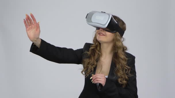 Žena s brýlemi virtuální reality na hlavě na šedém pozadí ve studiu. — Stock video