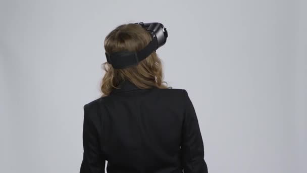 VRコンセプト。グレーの背景に仮想現実ゴーグルを持つ女性 — ストック動画